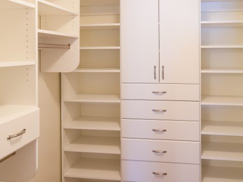 Custom white wood cabinetry in a walk in closet