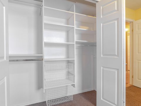 Square frame Empty white built in closet or wardrobe interior. Empty white built in closet or wardrobe interior in an unfurnished bedroom with the doors open showing shelves and rails for clothes